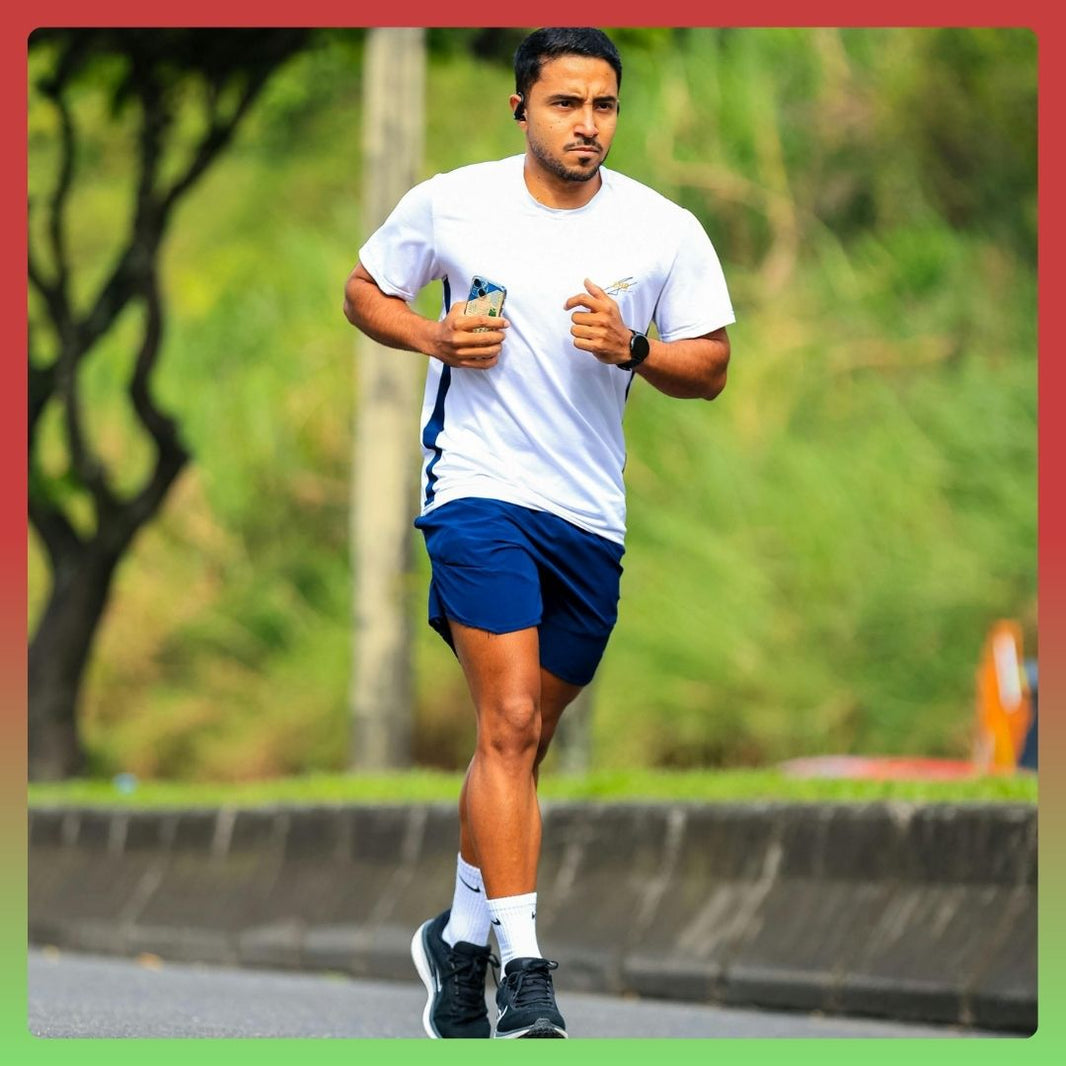 Focused man running on road wearing white tshirt and blue shorts during outdoor fitness training